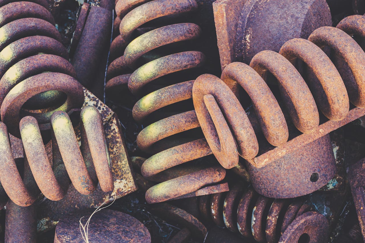 Detailed view of weathered and rusted metal springs in a scrapyard setting.