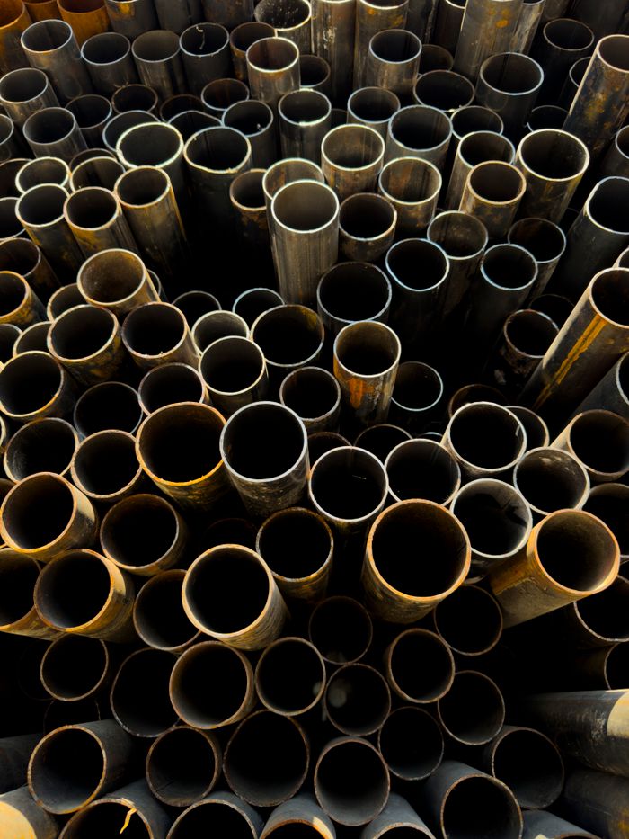 About A detailed view of stacked rusty metal pipes in an industrial setting, showcasing decay and grunge.
