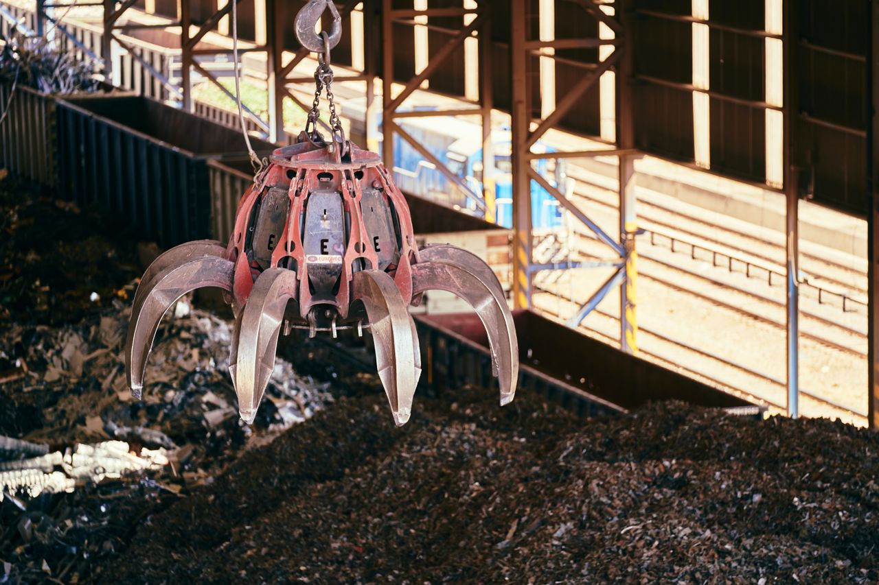 A claw crane inside a recycling facility lifting scrap metal, highlighting industrial processes.