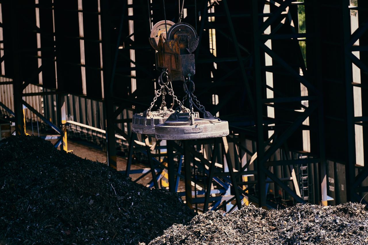 About Overhead view of industrial magnet lifting scrap metal in recycling plant.
